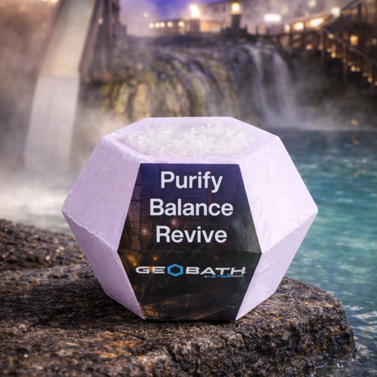 Geobath Geode Bath Bomb with 'Purify Balance Revive' text and GeoBath branding in front of a water feature.