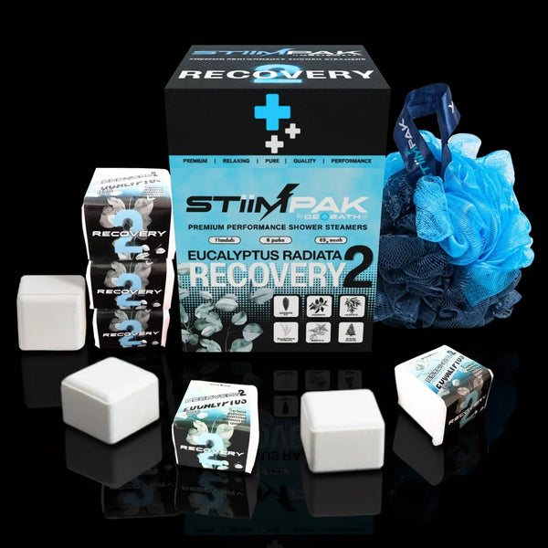 STiiMPAK Recovery 2 premium performance shower steamers set, featuring a black and blue product box, multiple white cube-shaped steamers, and a blue loofah sponge on a solid black background.
